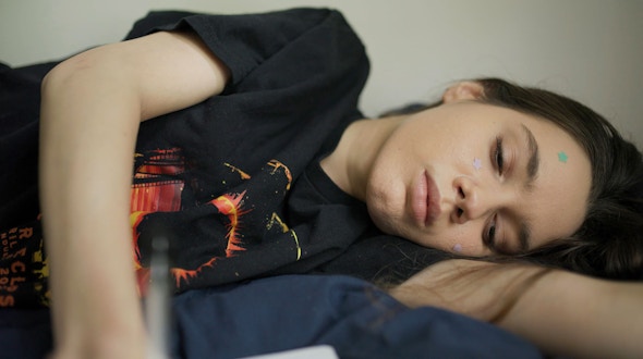 Girl lying on her side on a bed.