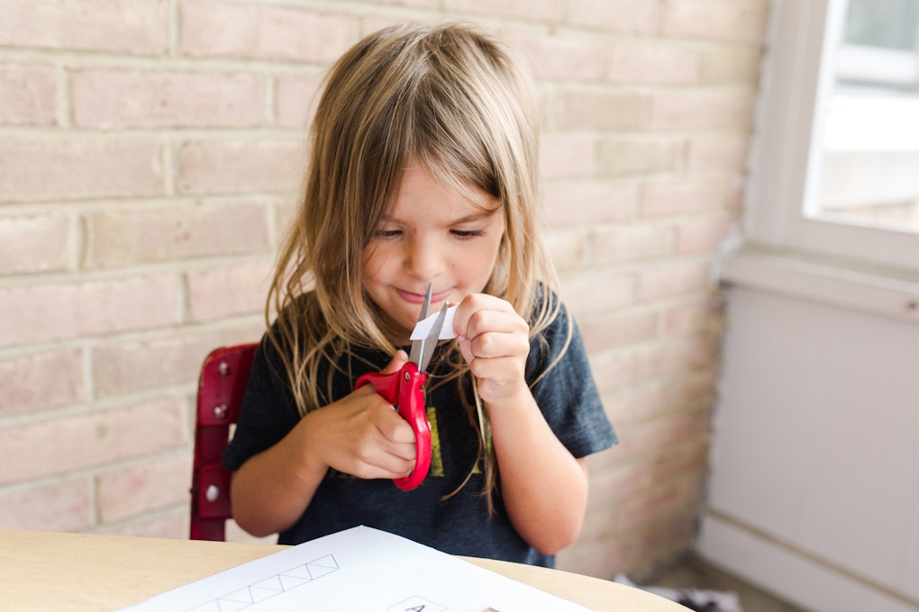 A little girl practices using scissors