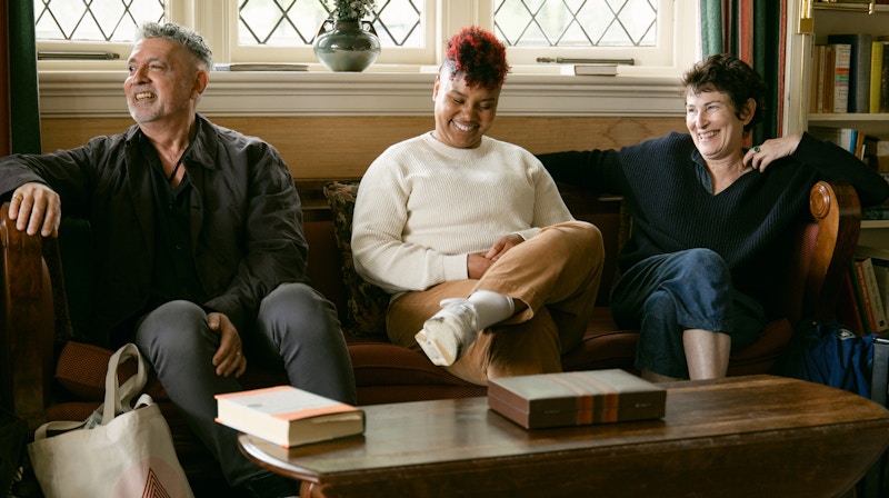 Three people laughing in a sunlit room