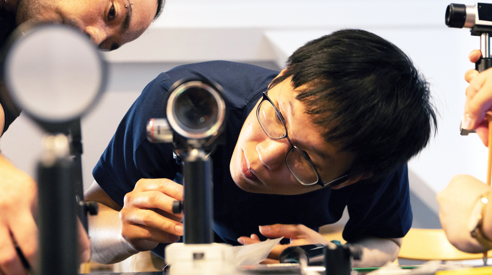 A photo of a student looking into a benchtop microscope.