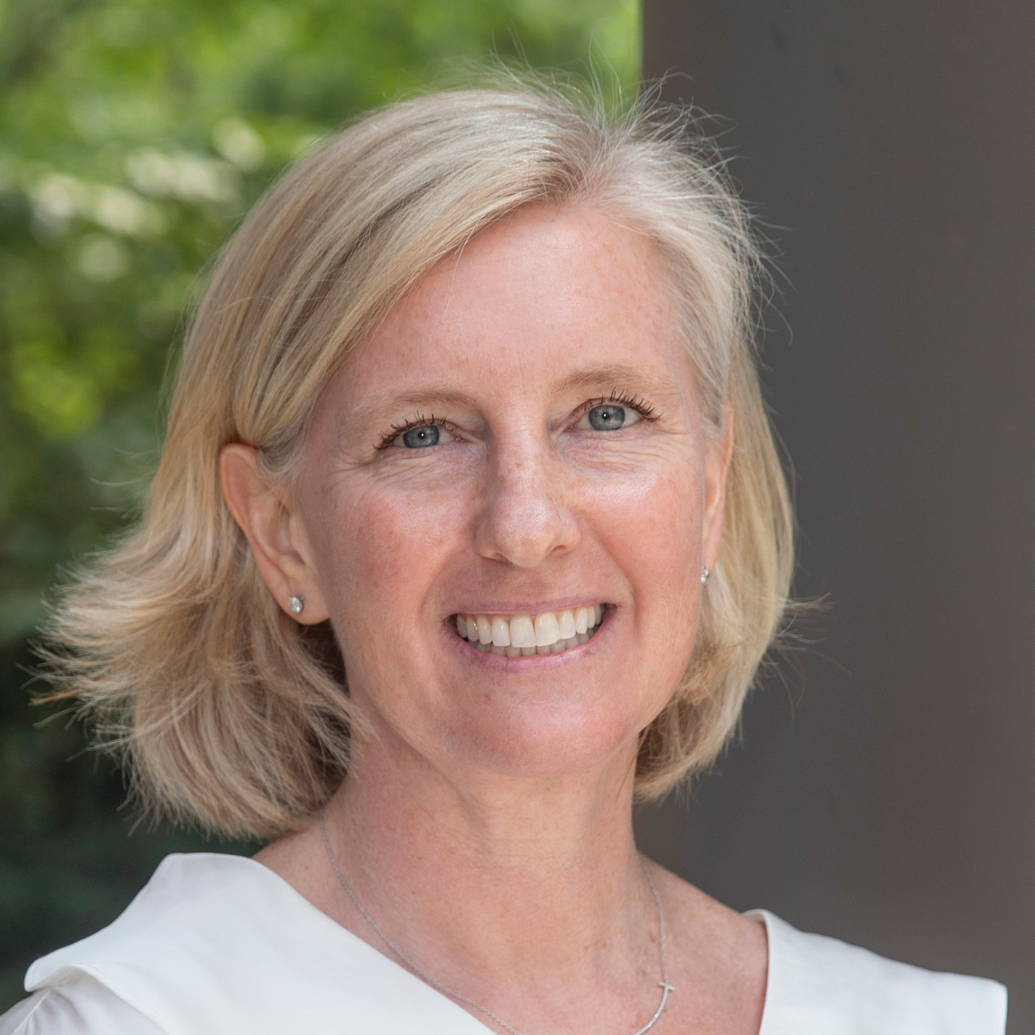 Hopi Hoekstra looks at the camera. Behind her, out of focus, is a column and foliage.