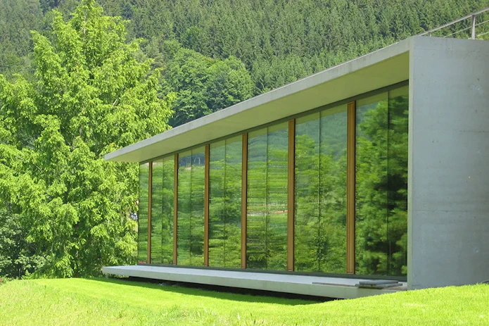 A photo of the north side library extension at the Mathematisches Forschungsinstitut Oberwolfach (MFO, Oberwolfach Research Institute for Mathematics) showing a mostly glass building in a green landscape.