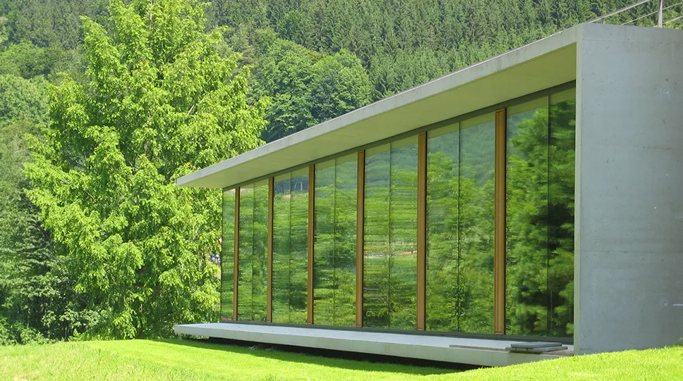 A photo of the north side library extension at the Mathematisches Forschungsinstitut Oberwolfach (MFO, Oberwolfach Research Institute for Mathematics) showing a mostly glass building in a green landscape.
