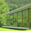 A photo of the north side library extension at the Mathematisches Forschungsinstitut Oberwolfach (MFO, Oberwolfach Research Institute for Mathematics) showing a mostly glass building in a green landscape.