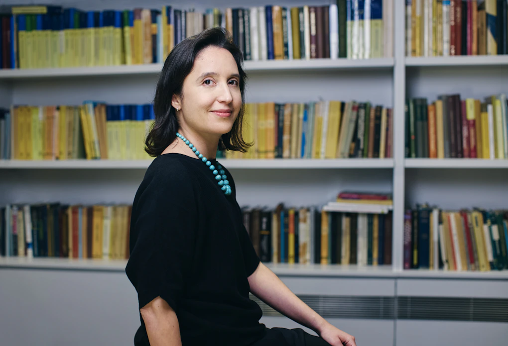 A photo of Pilar Cossio sitting in front of a shelf of math books.