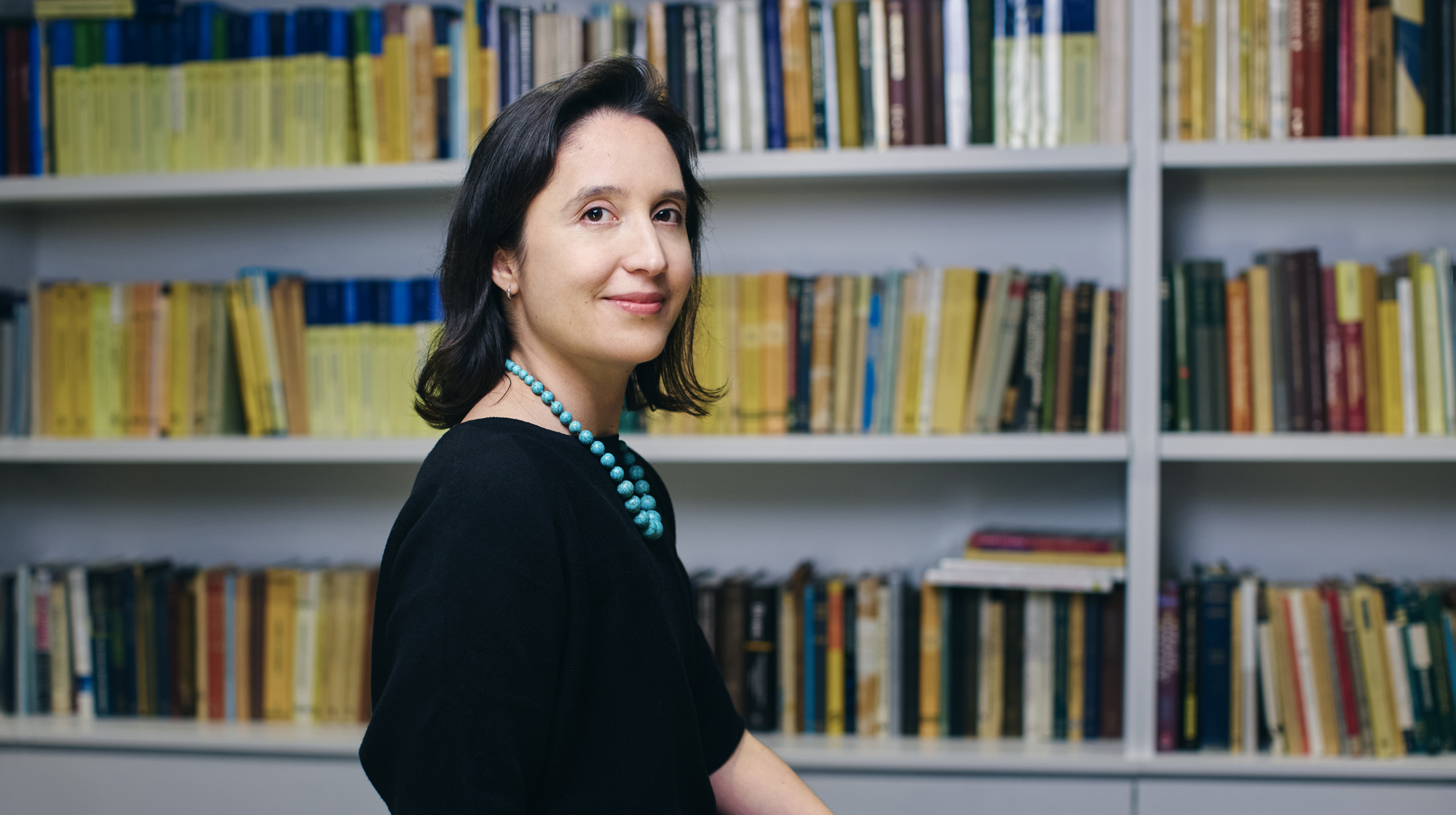 A photo of Pilar Cossio sitting in front of a shelf of math books.