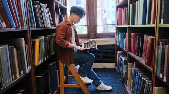 Photo of Kevin Hu sitting in the library at Columbia University