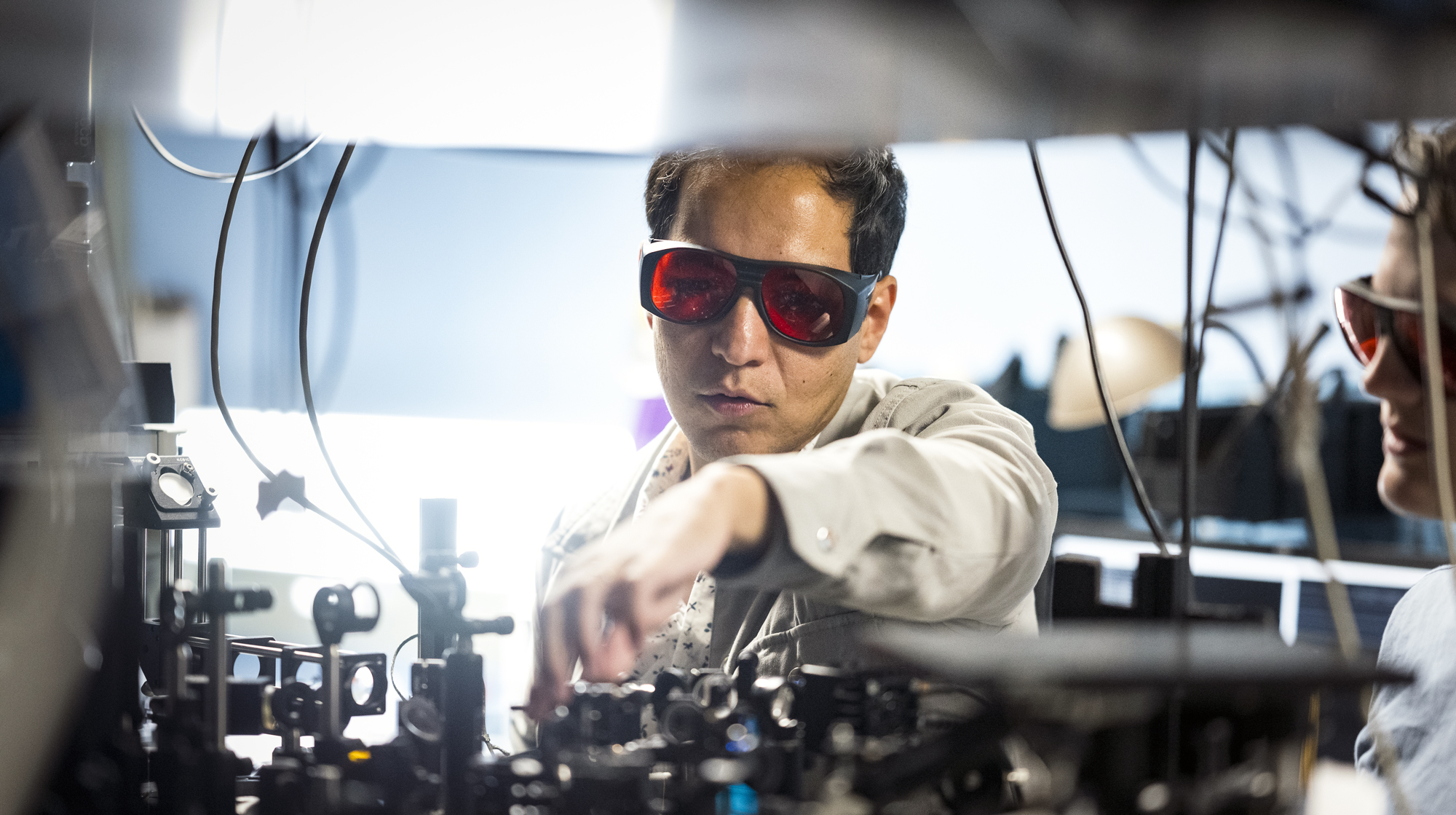 A photo of Axel working on his lab equipment with protective goggles on.