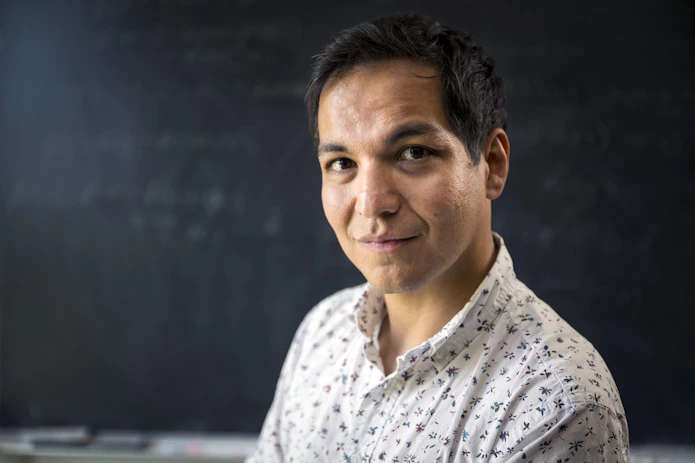 A portrait of Axel in a short sleeve white shirt smiling at the camera.
