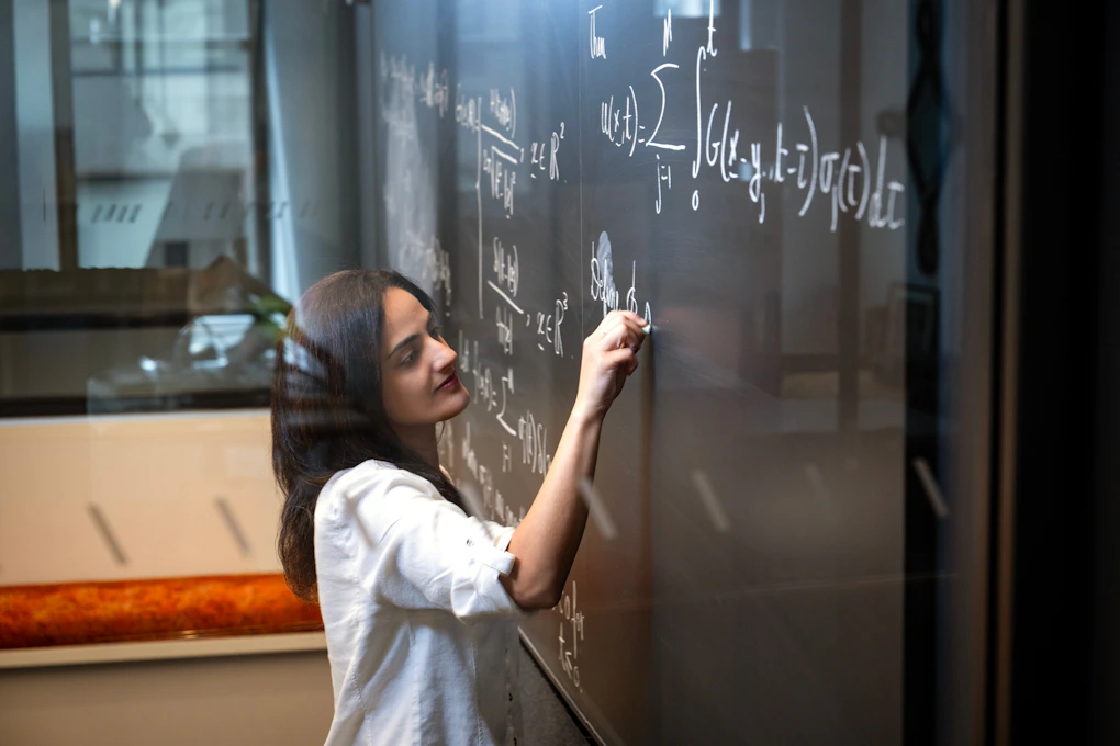 A photo of Nour Al Hassanieh writing on a chalkboard.