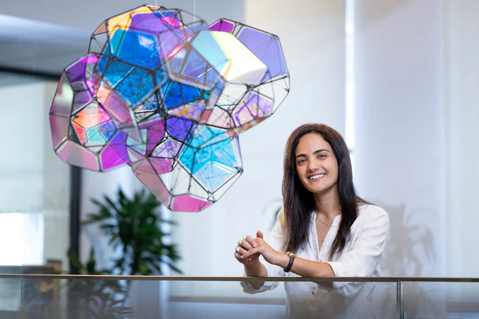 A photo of Nour Hassanieh standing in front of colorful sculpture.