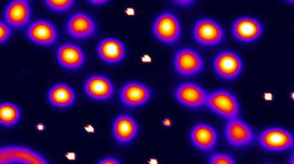 Image of electrons shown as glowing orange circles on a black background.