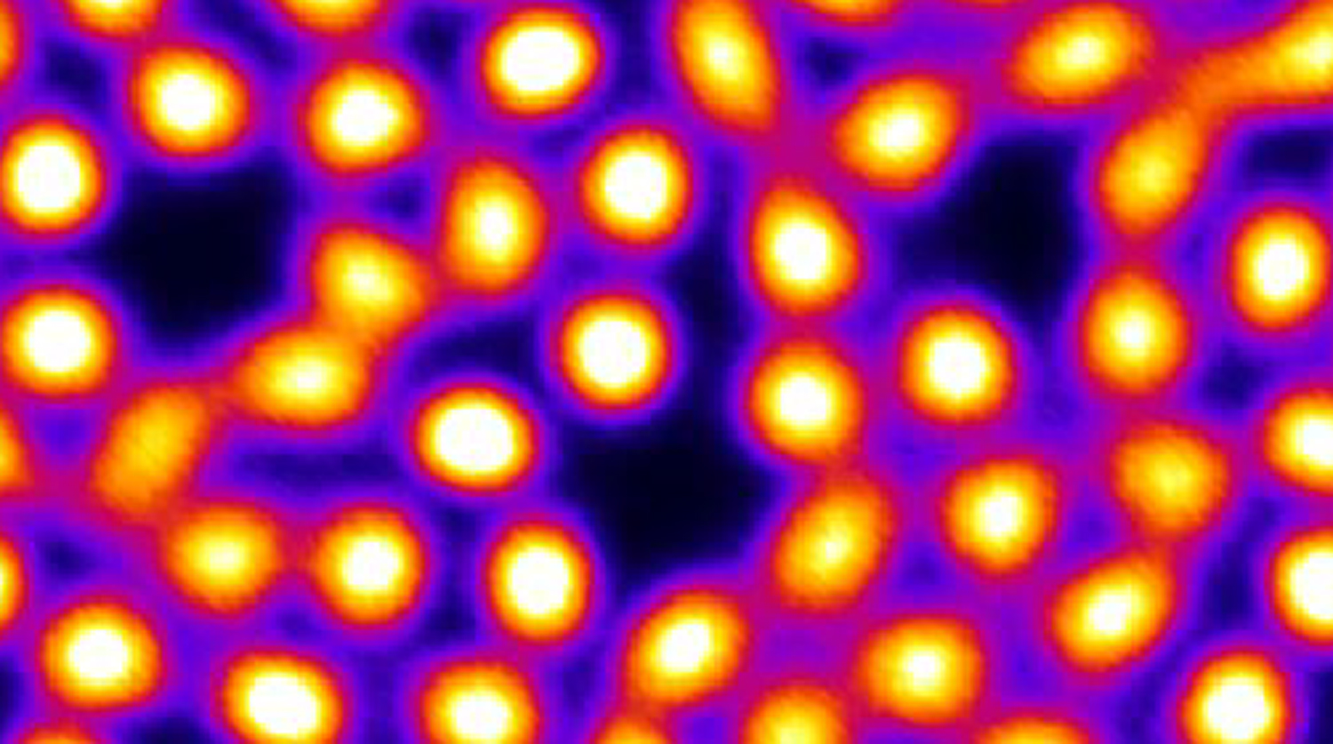 Image of electrons shown as glowing orange circles on a black background.