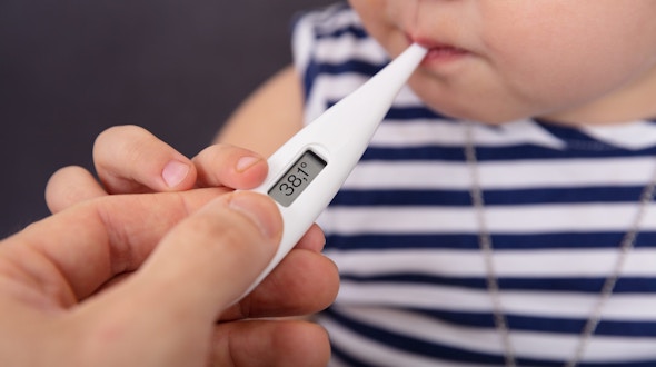 Close-up Of Person's Hand Checking Temperature Of Sick Girl While Using Digital Thermometer