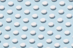 Abundance of white colored pills repetition on light blue background