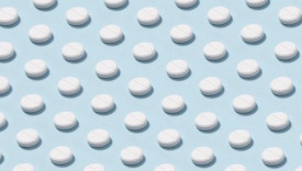 Abundance of white colored pills repetition on light blue background