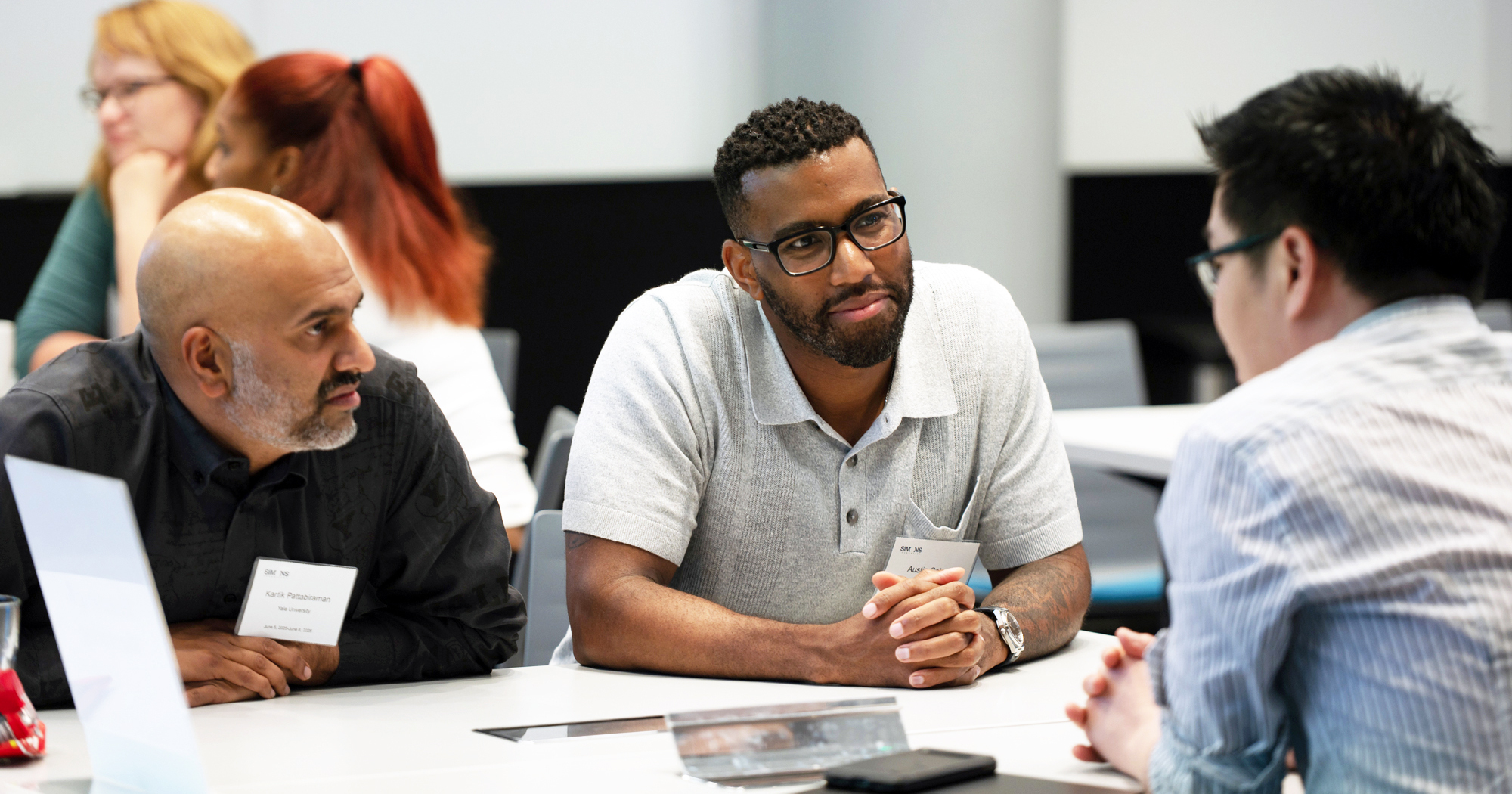 Image of three fellows talking at a table