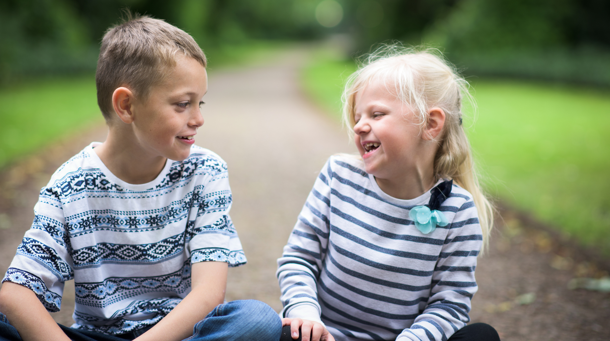 A little boy with Autism and his sister sitting playing together laughing and being happy, smiling and cute.