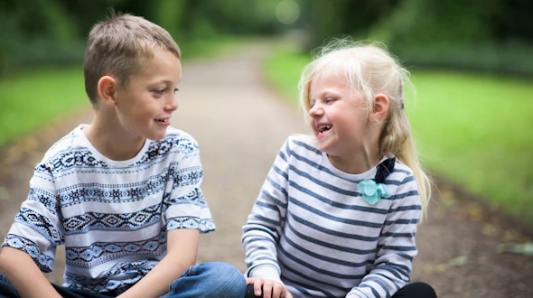 A little boy with Autism and his sister sitting playing together laughing and being happy, smiling and cute.
