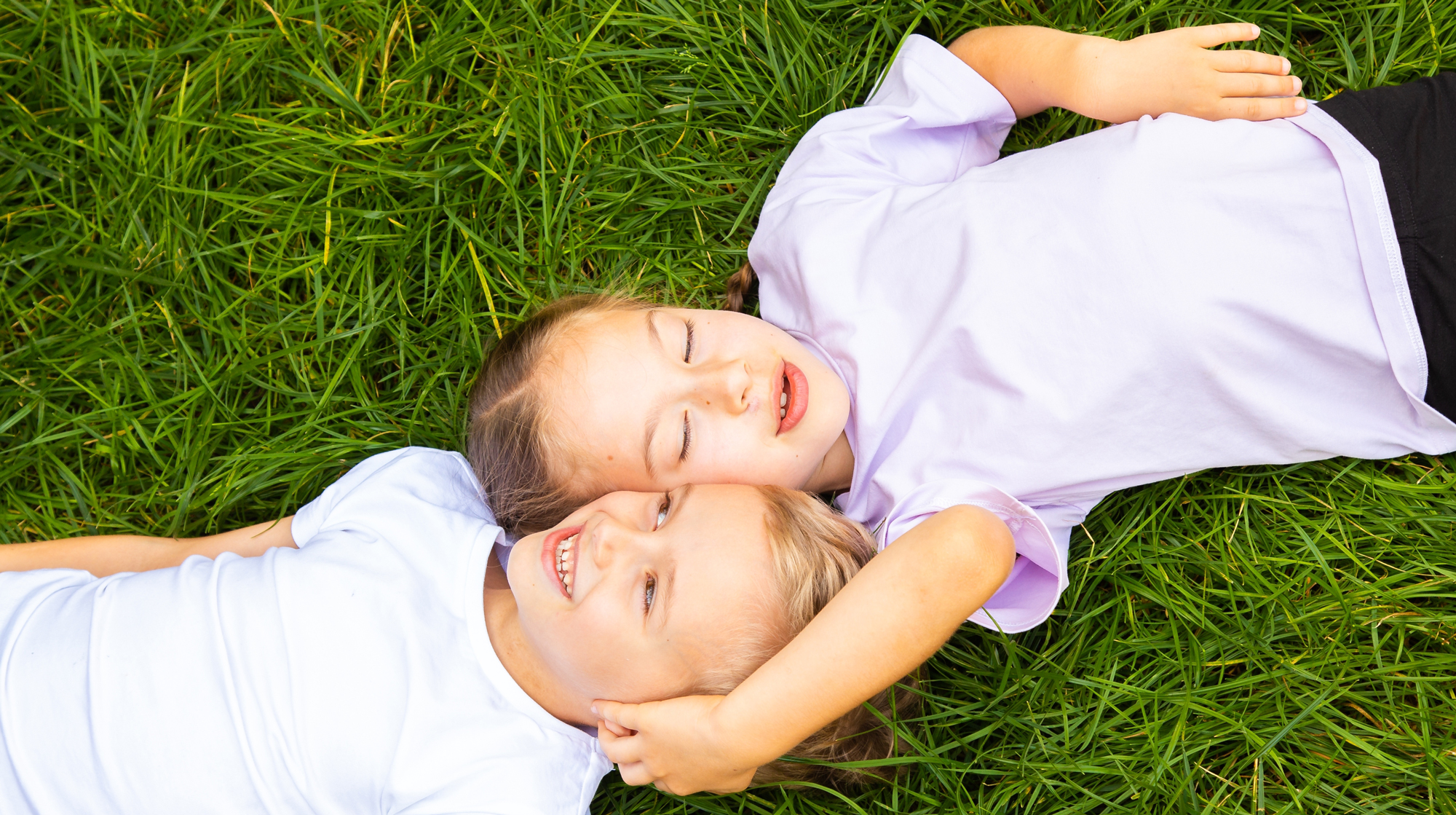 A photo of a boy and girl child lying in the grass.