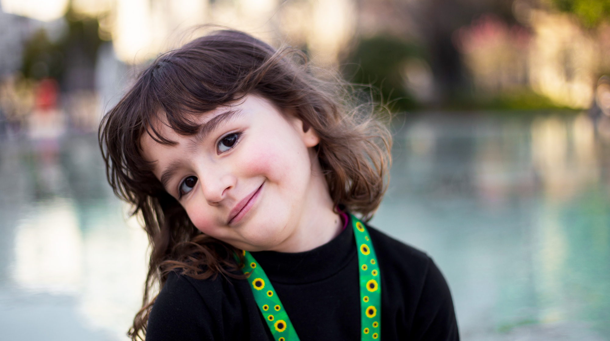 Photo of a cute little girl with a autism identification lanyard of sunflowers on a green background.